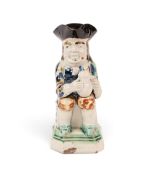 A small pearlware Toby jug, c.1790-1800, seated with a foaming jug of ale, his coat patterned in blu