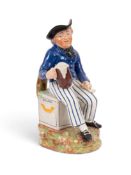 An American Sailor Toby jug, c.1810-20, wearing a blue uniform with yellow buttons and seated on a s
