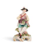 A Chelsea figure of a vintner, c.1759-65, seated with a basket of grapes on his lap, raised on a scr