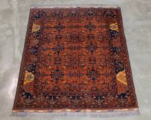 AN AFGHAN ORANGE GROUND TRIBAL WOOL RUG (177 x 145CM)