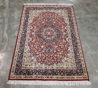 A RED AND IVORY GROUND MEDALLION WOOL RUG (180 x 120CM)