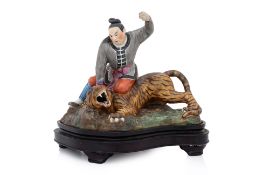A PORCELAIN MODEL OF A MAN SUBDUING A TIGER