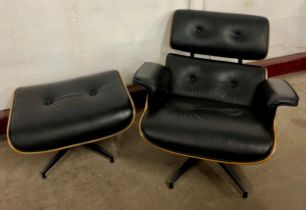 A Charles & Ray Eames style black leather and simulated rosewood revolving lounge chair and ottoman