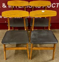 A set of four teak and black vinyl chairs