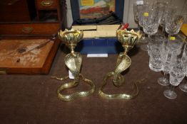 A pair of brass candlesticks in the form of cobras