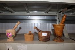 A burr wood pestle and mortar together with three other wooden pestles and mortars