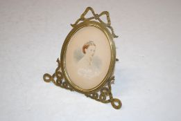 An oval miniature portrait contained in brass frame with ribbon tied decoration