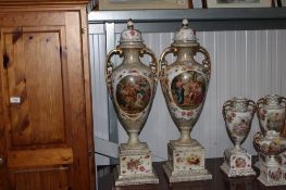 A pair of twin handled floral decorated continental porcelain urns raised on pedestal bases with