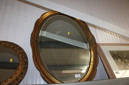 A gilt framed and bevel edged oval wall mirror