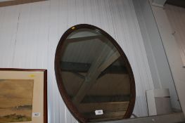 A wooden framed oval wall mirror
