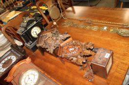 Two cuckoo clocks; a black slate style mantel clock and a wooden cased mantel clock