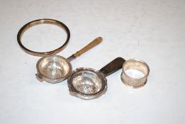 A silver napkin ring; a circular silver mount, 42gms total weight; and two silver strainers