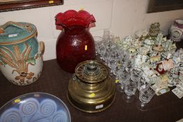 A brass oil lamp with cranberry dimpled shade