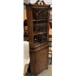 A mahogany reproduction freestanding corner cupboard with upper glazed doors over single door base,
