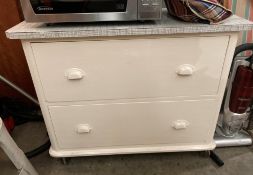 White painted pine two drawer chest of drawers with formica top and on castors,