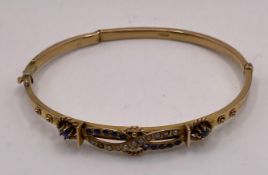 A 9ct gold 375 early 20th century hinge bangle with seed pearls and colour stones with broken arm,