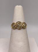 A 18ct gold swirl pattern design ring set with one diamond two moissanite all surrounded by seed