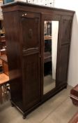 An early 20th century oak three door wardrobe with central mirrored door,