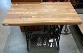 A Singer treadle sewing machine base converted to a table with a wood top,