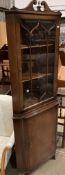 A mahogany reproduction freestanding corner cupboard with upper glazed doors over single door base,