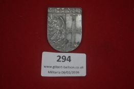 German patriotic badge in white metal, shield-shaped, decorated with cross and eagle, edge inscribed