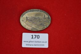 German regional commemorative tinnie, oval form depicting a riverside townscape and inscribed “