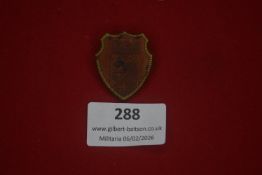 German Third Reich period shield-shaped tinnie, copper-toned face with applied gilt border,