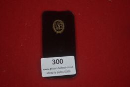 German lapel badge on original display card, bearing an oval wreath with intertwined initials to the