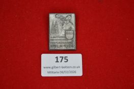 German artillery-related commemorative badge, rectangular, showing a uniformed soldier sounding a