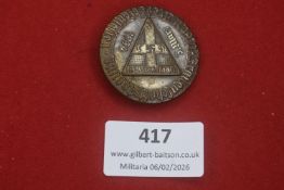 Third Reich tinnie, circular form with triangular emblem bearing swastika and dated 1934, with