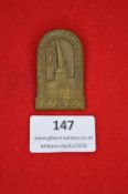 German commemorative tinnie, arched form depicting a church and townscape, with inscriptions “