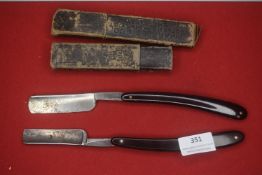 Two vintage straight razors, each with black scales, one bearing a George Wostenholm & Son,