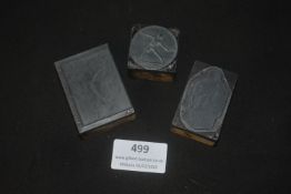 Three carved printing or embossing blocks, likely linoleum or similar material mounted on wooden