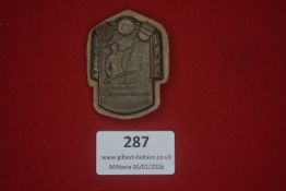 German Third Reich period tinnie, cast metal example depicting armed figure with agricultural