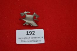 German tinnie-style badge, depicting crossed axes and tools over a helmet motif. Reverse with