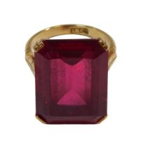 A single stone dress ring, set with a rectangular cut heat treated ruby, in a four double claw