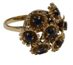 A 20thC floral cluster ring, formed as seven floral sections, on a frame, each with a round