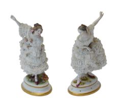 A pair of Volkstedt porcelain lace figures of ladies dancing, in flower-encrusted crinoline dresses,