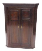 An 18thC oak hanging corner cupboard, the panelled doors revealing a fitted interior of serpentine