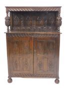 An 18thC style oak court cupboard, the upper section with heavily carved canopy, held on heavy