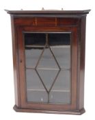 An Edwardian mahogany and boxwood strung hanging corner cupboard, the dentil top raised above an