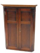 A 19thC oak hanging corner cupboard, the two panelled doors revealing a fitted interior, with