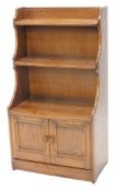 A late 20thC Ercol waterfall bookcase, with three shelves above double cupboards, 116cm high, 62cm