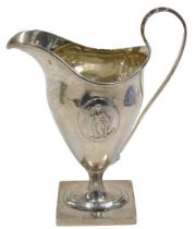 An Edward VII silver cream jug, with strap handle, helmet shaped body, inverted stem and oval