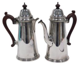 A pair of Elizabeth II silver water jugs, each with domed lids, shaped ear handles and plain
