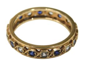 An eternity ring, set with sapphire and cz, yellow metal pierced design, with rubbed markings,
