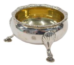 A George VI silver three footed salt, with shaped rim, silver gilt interior, plain circular body and