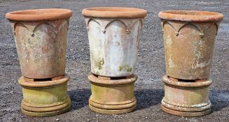 Three large Italian terracotta planters with Gothic arch detail raised on circular terracotta