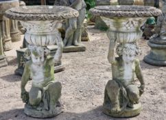 Pair of weathered reconstituted stone garden urns with lobed bowls and foliate swag detail, raised