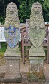 Pair of weathered reconstituted stone garden statues of seated lions with shields, raised on